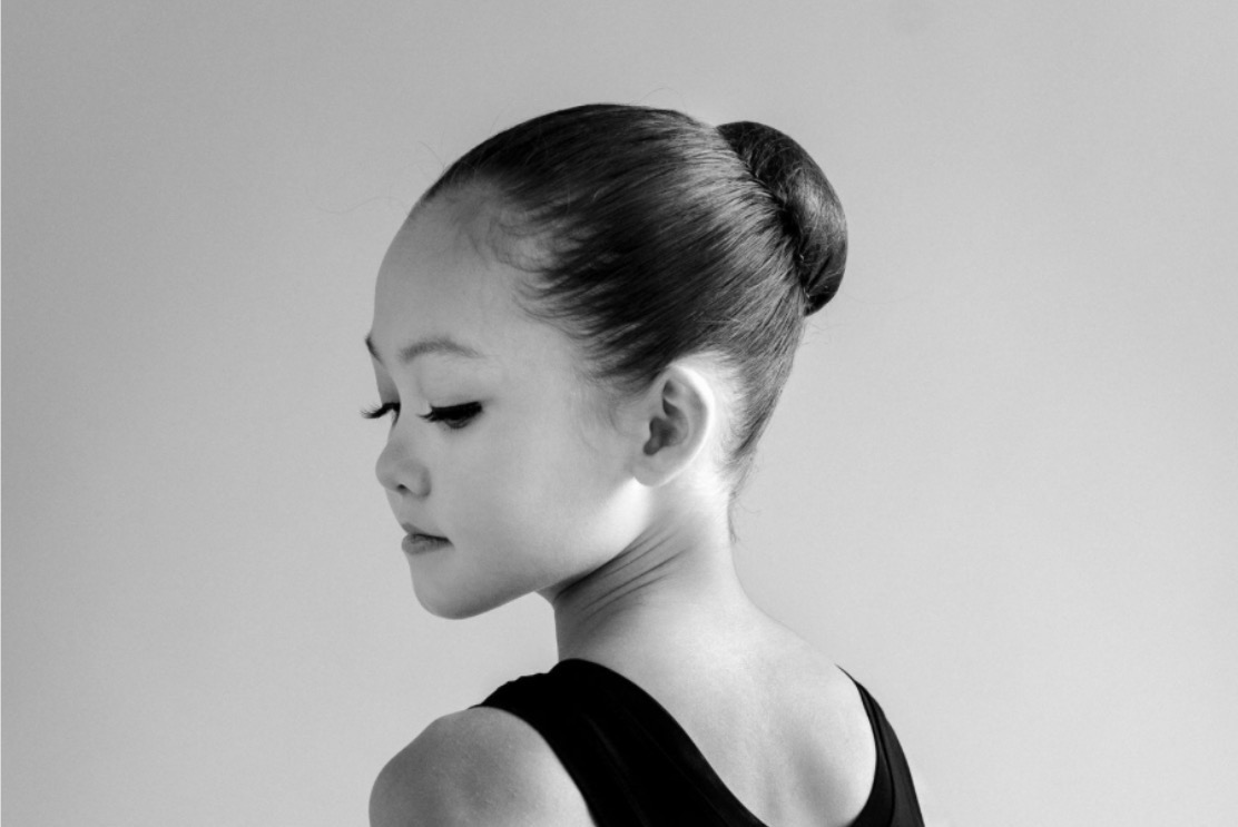 Black-and-white side view of a dancer with her hair slicked back into a neat ballet bun.