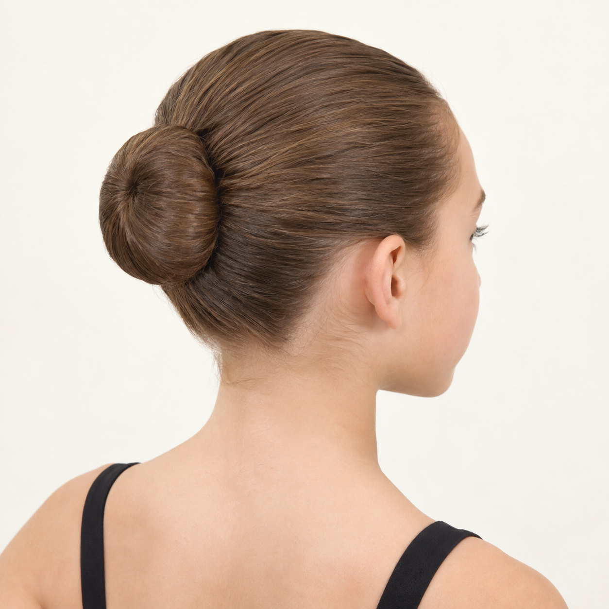 Rear three-quarter view of a girl with smooth, slicked-back hair secured in a neat ballet bun.