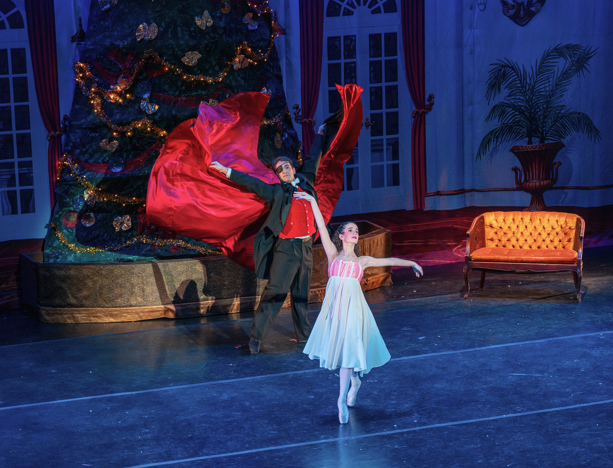 Two CRYB dancers performing a Nutcracker party scene beside a Christmas tree