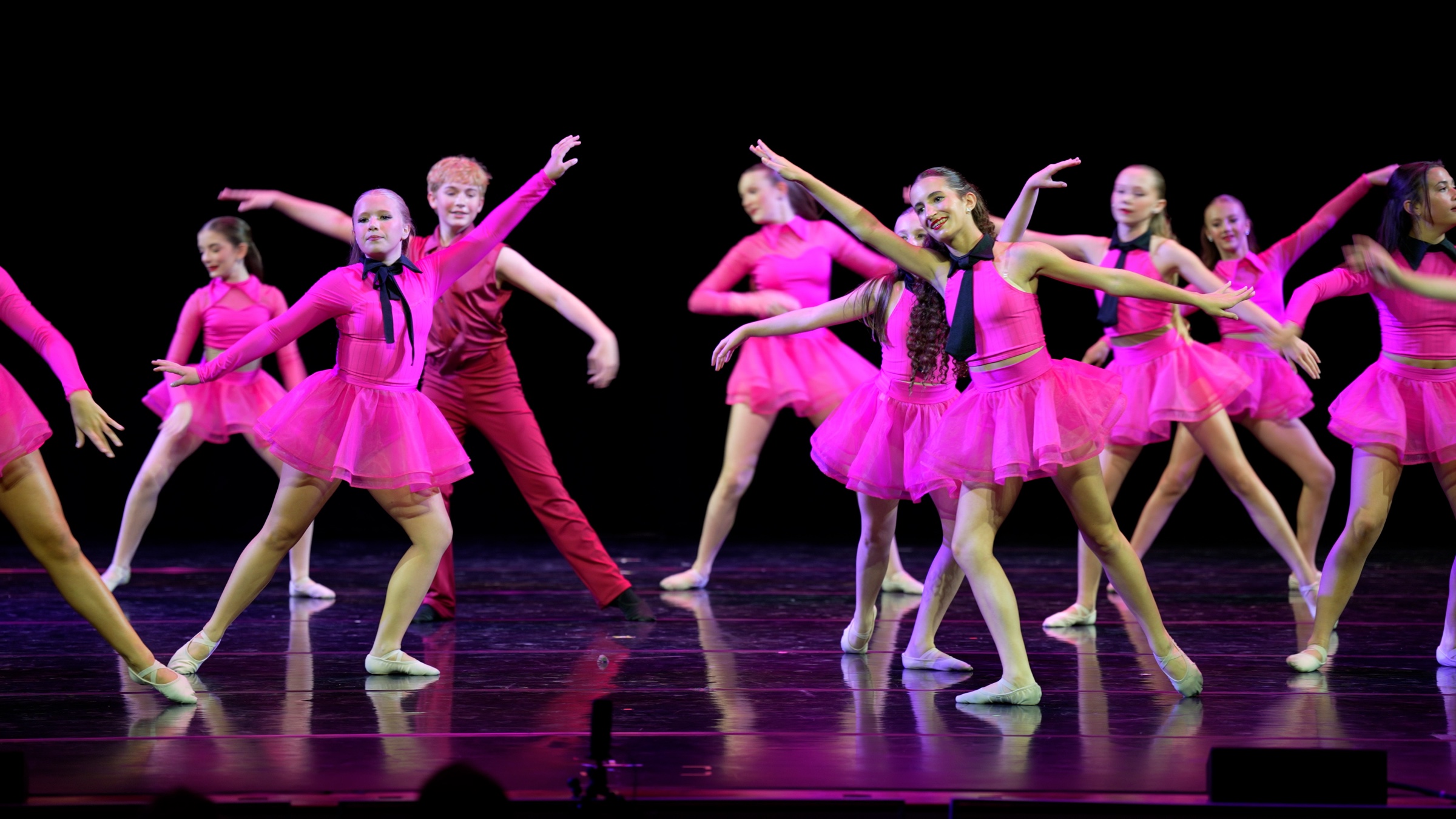 CRYB dancers performing together on stage in bright pink costumes